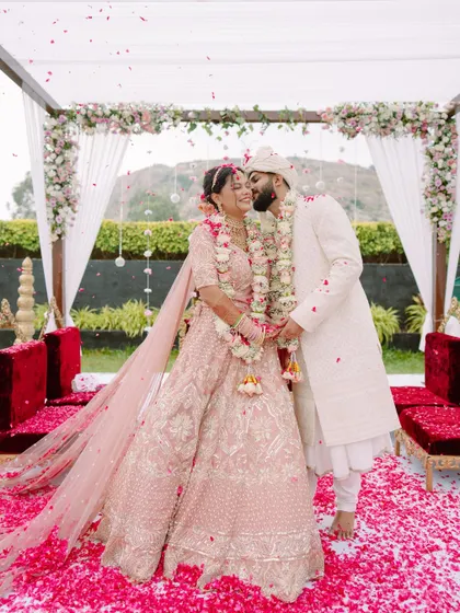 Pure elation under a shower of petals. This is the peak of the celebration, a vibrant, joyous moment from a beautiful North Indian wedding ceremony that we captured in all its colorful glory.