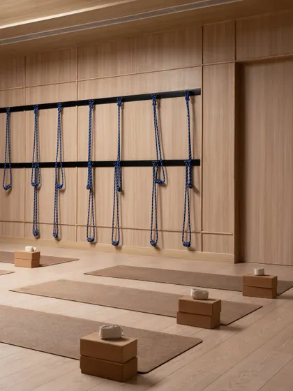A wall of yoga ropes hangs in perfect rhythm at the BeWell studio. This functional element is treated as a design feature, its repetition and texture adding to the room's serene and orderly character.