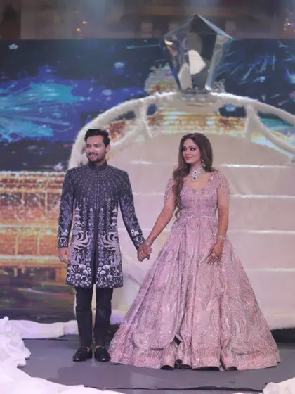 A fairytale moment from their reception. The couple stands hand-in-hand on a grand, winter-themed stage, looking like the king and queen of their own magical kingdom.
