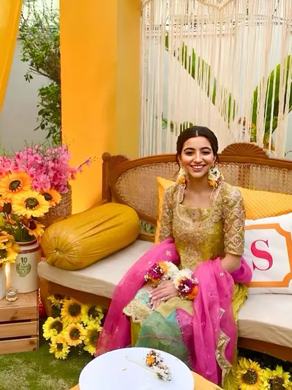 The bride-to-be enjoying her sunflower-themed intimate ceremony. The decor is personalized with custom monogrammed cushions, adding a special touch to her seating area.
