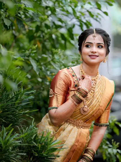 A beautiful bridal portrait amidst lush greenery, the soft light highlighting the bride's features and her stunning traditional attire.