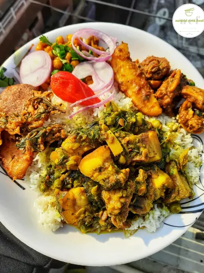 A delicious bowl of pork chagempomba, a traditional Manipuri curry made with fermented soybeans, served over rice with many other tasty sides.