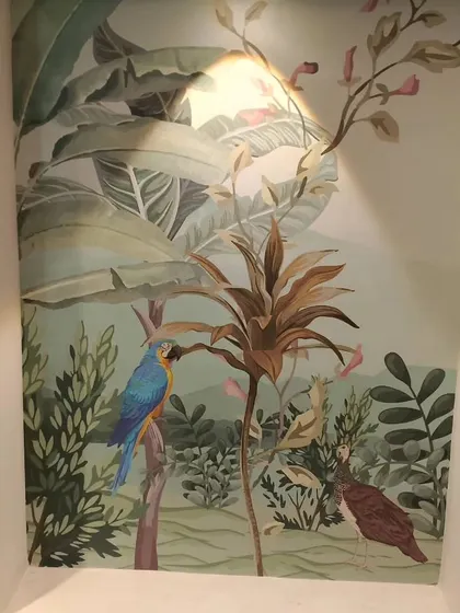 A tropical mural with a parrot, installed in a small wall niche. This shows how wallpaper can turn small, awkward spaces into art features.