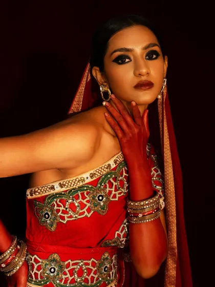 A close-up beauty shot from the red bridal series, focusing on the dramatic eye makeup and the model's confident expression.