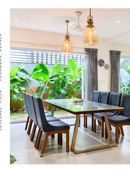 The dining room at Lovedale Villa is surrounded by greenery, with large windows providing a beautiful, natural backdrop for meals.