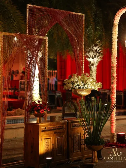 An artistic installation using red and gold thread to create arch-like structures, placed over rustic wooden cabinets.