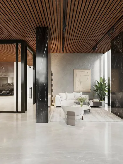 Another view of the lobby, showing the seamless connection between the entrance, the waiting area, and the private parking visible through a glass wall. The design uses a careful selection of materials to create a cohesive and luxurious narrative.