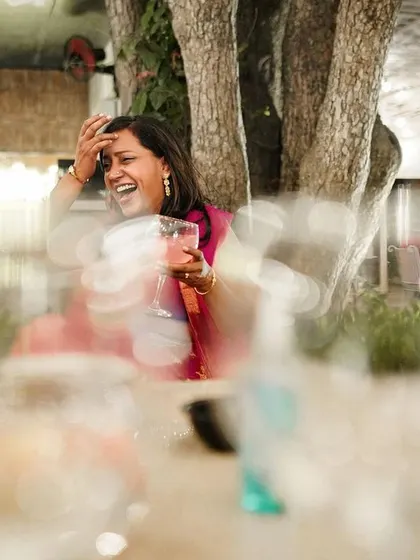 A guest's candid laughter during a reception, captured with a creative use of foreground bokeh.
