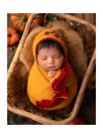 An overhead view of the baby nestled in a basket for the autumn-themed shoot.