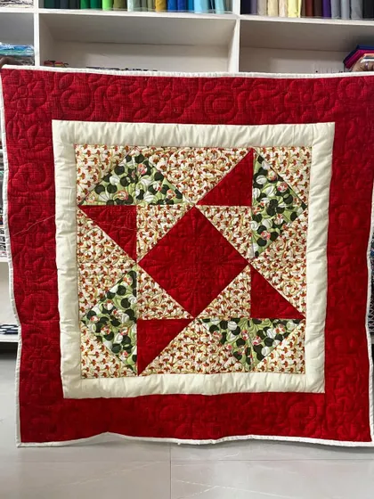 A classic beginner baby quilt in red and cream, featuring a simple star pattern. This timeless design is perfect for a new baby.