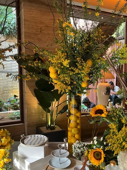 A tall vase arrangement of lemons and yellow oncidium orchids, part of a larger summer-themed event. This piece adds height and a touch of Italian-inspired elegance to the decor.