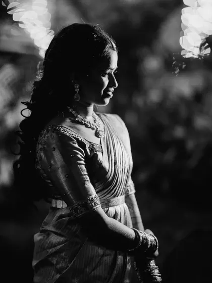 A timeless black and white portrait capturing the elegance of the reception look. The focus is on the silhouette, the texture of the saree, and the beautifully styled hair.