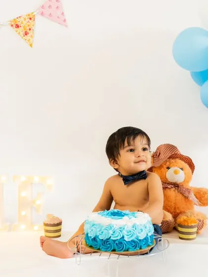 A classic first birthday portrait with a beautiful blue cake and festive balloons. This little one is ready to celebrate his big day in style.