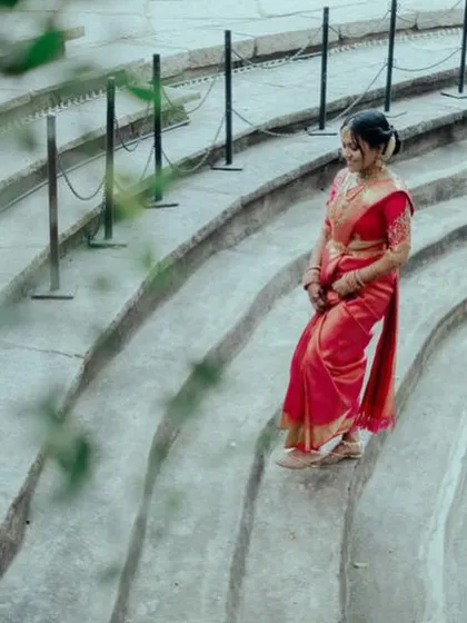 A bride in a red saree descends the curved stone steps of the amphitheater, a dramatic and unique photo opportunity.