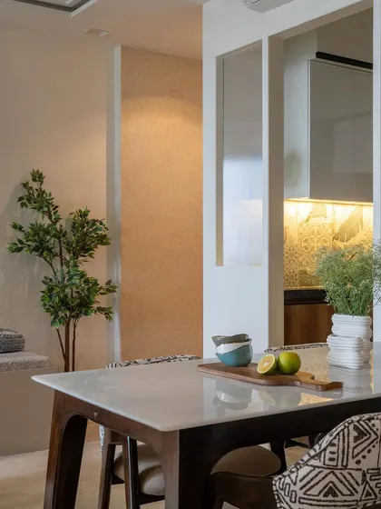 An unseen shot from 'House in the Hills', showing the dining table with a view into the kitchen. The open-plan design creates a sense of connection between the spaces.