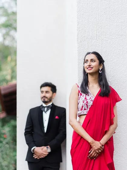 A stylish portrait of the couple against a white wall, their formal wear creating a classic look.