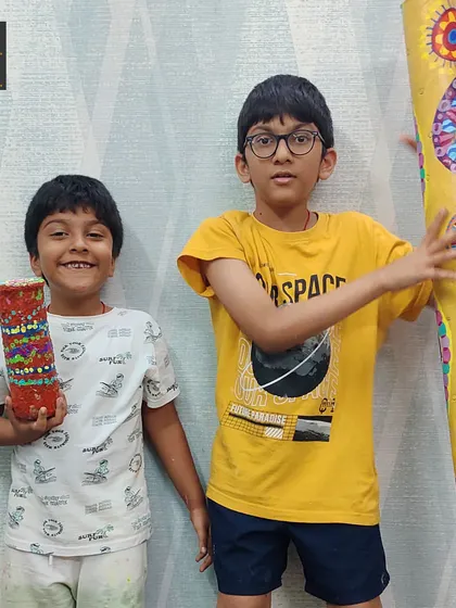 These brothers proudly display their finished rain sticks, one small and one large. The project involved building, painting, and filling the sticks to mimic the soothing sound of falling rain.