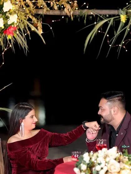 A romantic candlelit dinner setup on the beach for a pre-wedding shoot. The fairy lights and floral arch create a magical atmosphere for a perfect proposal or celebration.