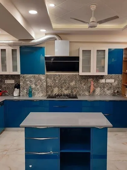 A bold and spacious U-shaped kitchen with an island. The vibrant blue gloss cabinets are paired with white upper cabinets and a patterned backsplash for a unique and personalized look.