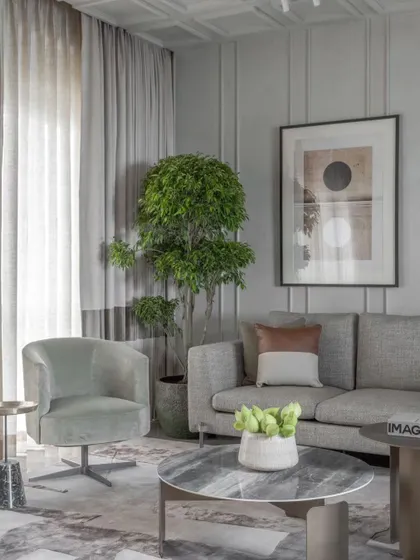 This view highlights the calm, neutral palette of the living room, punctuated by a lush indoor tree. We believe in creating timeless spaces that don't bow to trends.