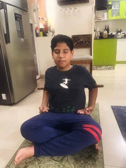 A young boy practices a seated meditative pose, demonstrating the calm and focus that yoga can bring to children.