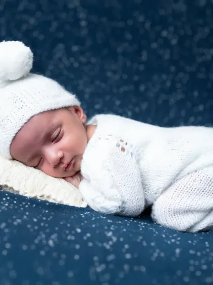 A classic "tushy up" newborn pose, with the baby sleeping on his tummy on the starry background.