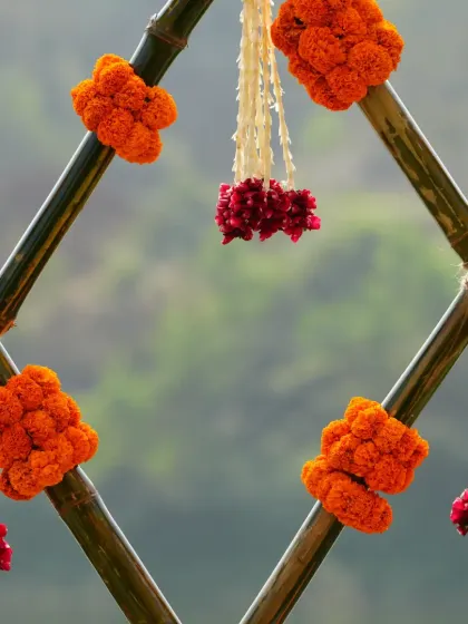 A close-up of a bamboo lattice detail from a Haldi backdrop, adorned with marigold and tuberose tassels.