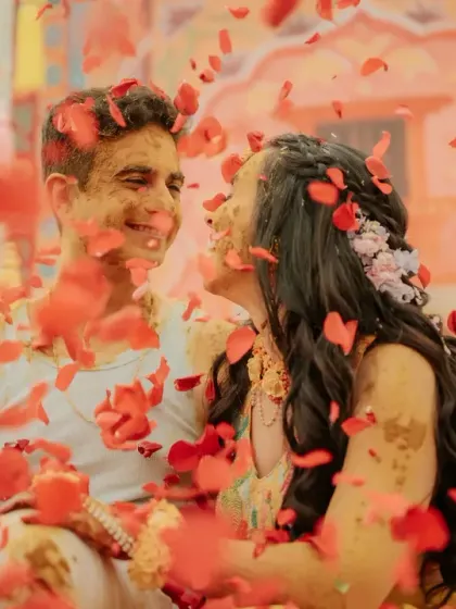 A close-up of the couple sharing a sweet moment amidst a shower of rose petals during their Haldi.