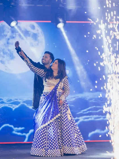 A picture perfect moment with a 'dancing on the moon' backdrop and cold pyro effects. I help plan these details to make your couple's performance a visual spectacle.