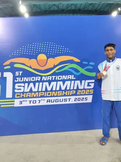 Sharan S posing with his gold medal against the championship banner.