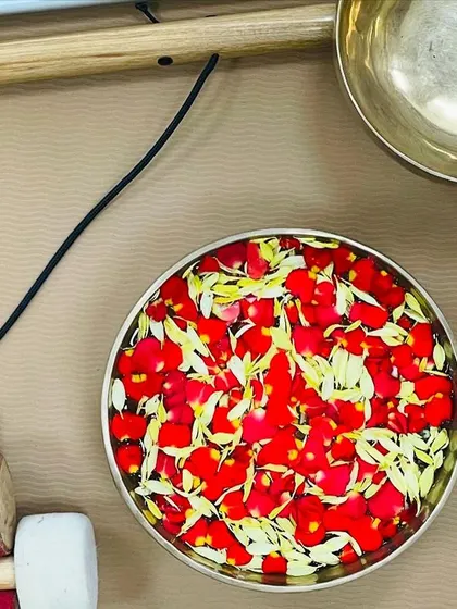 A singing bowl filled with flower petals. This is a practice of offering beauty and gratitude. The water in the bowl can also be "charged" with the vibrations of the sound for healing purposes.