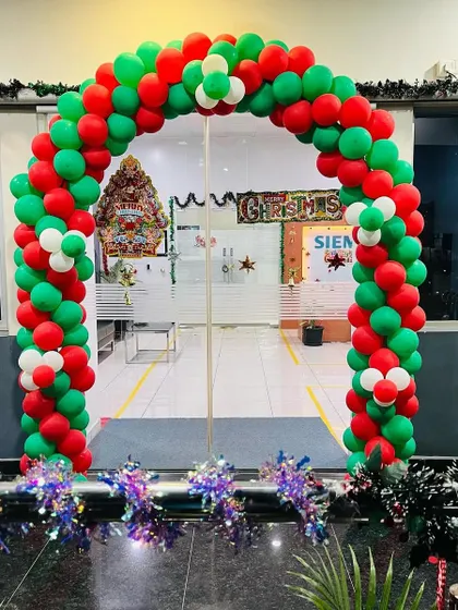A grand red, green, and white balloon arch designed for a corporate office entrance during the Christmas season. This festive decoration welcomes employees and visitors, complete with sparkling tinsel at the base for an extra touch of holiday cheer.