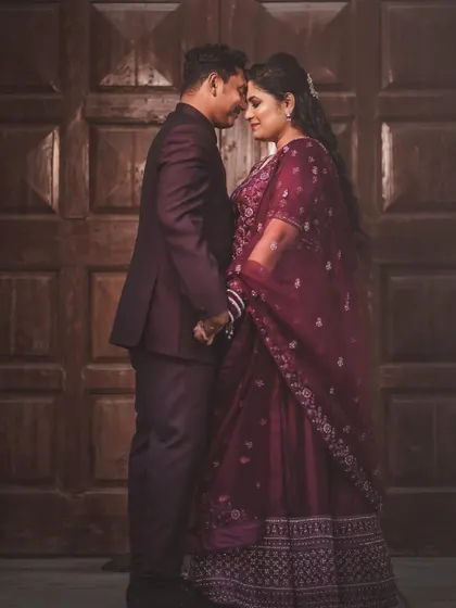 A classic, romantic portrait of the couple. Their foreheads are touching as they stand before a large wooden door, creating a timeless and intimate image.