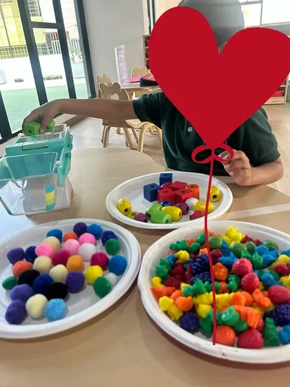 A child at Cambridge Juniors sorting colorful manipulatives. Activities like this are foundational for developing skills in patterning, counting, and classification.