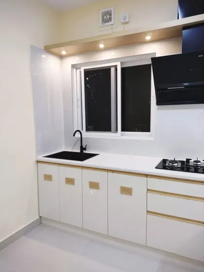 The sink and hob area of the serene white kitchen. The black faucet and hob create a striking contrast against the white countertop and backsplash, adding a touch of modern drama.