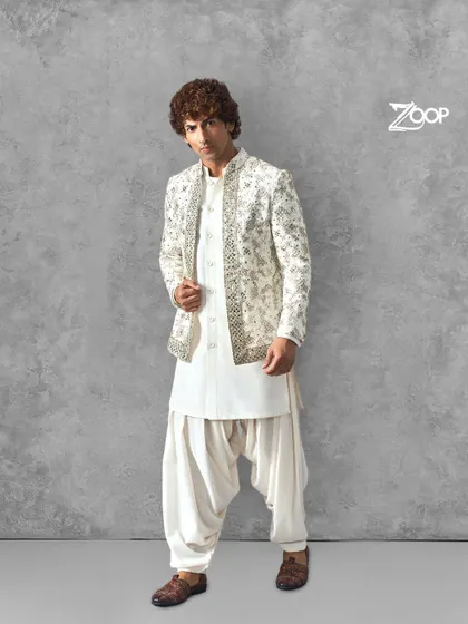 An all-white Pathani suit that exudes classic charm. The detailed embroidery on the jacket adds a layer of sophistication, making it a perfect choice for any grand celebration.