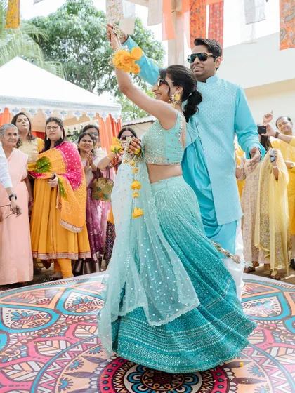 The couple dancing joyfully on a colorful dance floor during their Haldi celebration in Udaipur.