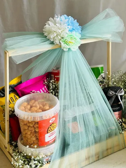 A large snack hamper for an engagement, elegantly wrapped in sea-green tulle. This is a perfect gift for the family to share and enjoy.