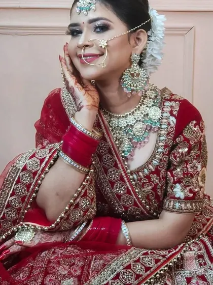 A happy bride smiling in her red lehenga and custom jewellery. The set features a Polki choker with light blue bead drops, adding a unique touch of colour.