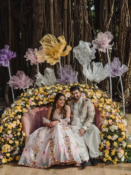 A beautiful portrait of the couple at their Mehendi, surrounded by a stunning floral installation and whimsical oversized paper flowers.