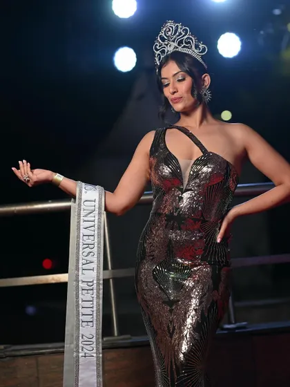 A confident pose from a pageant winner, showcasing her sash. This is a classic shot that highlights her title and achievement.
