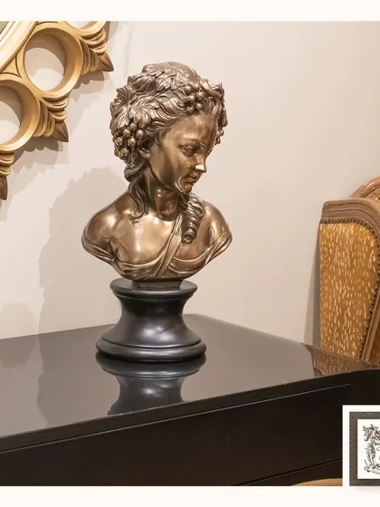 This graceful woman's visage sculpture, with a bronze finish and a classic pedestal, adds a touch of serene beauty to a modern console table. It's a minimalist yet impactful piece of art.