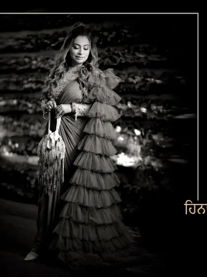 A dramatic black and white portrait of Heena in her ruffled saree, capturing a moment of quiet elegance.