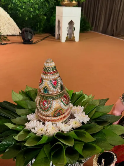 A beautifully decorated kalash on a bed of betel leaves and white flowers, perfect for poojas.