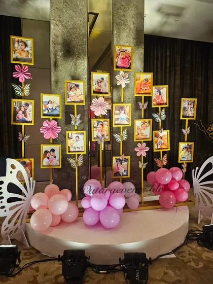 A beautiful and personal touch, this photo gallery displays pictures from the baby's first year on stands decorated with paper flowers and butterflies.
