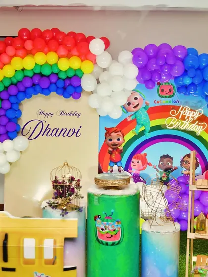 A fun Cocomelon setup with a rainbow balloon arch and themed pedestals.