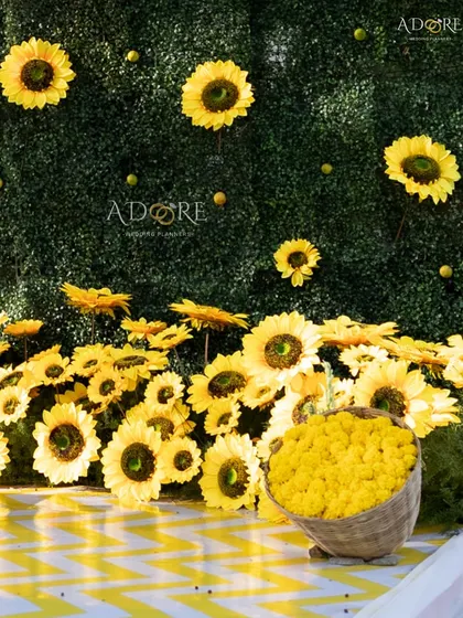 Another angle of the sunflower-themed Haldi decor, showing a basket of fresh yellow flowers ready for the ceremony, set against the vibrant sunflower wall.
