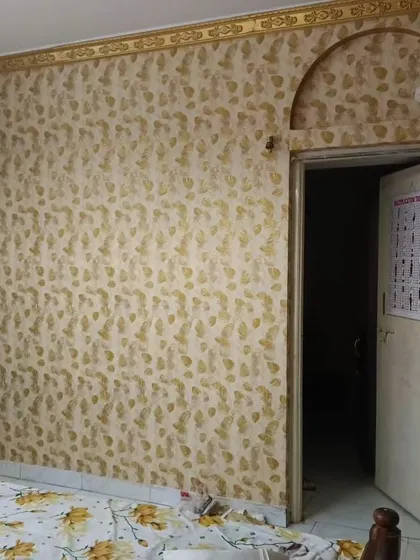 A bedroom with a gold leaf pattern wallpaper, creating a warm and luxurious atmosphere.