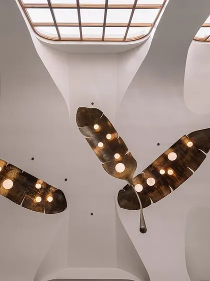 The ceiling at Rehethaan is a complex geometry of curves and vaults. Here, oversized, custom-made frond-like lights by Shailesh Rajput Studio add a dramatic, organic touch.