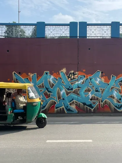 An auto-rickshaw rolling past my "KRYPT" piece in Ahmedabad. The art becomes part of the city's fabric, a backdrop to everyday life.